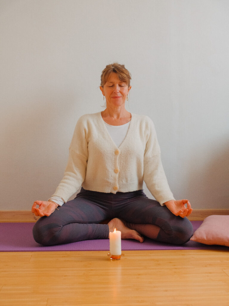 professeure assise dans une posture de méditation pendant une séance de yogathérapie
