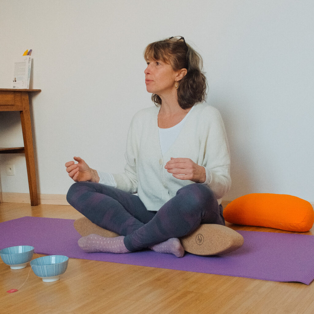 praticienne en yogathérapie assise en tailleur pendant une séance