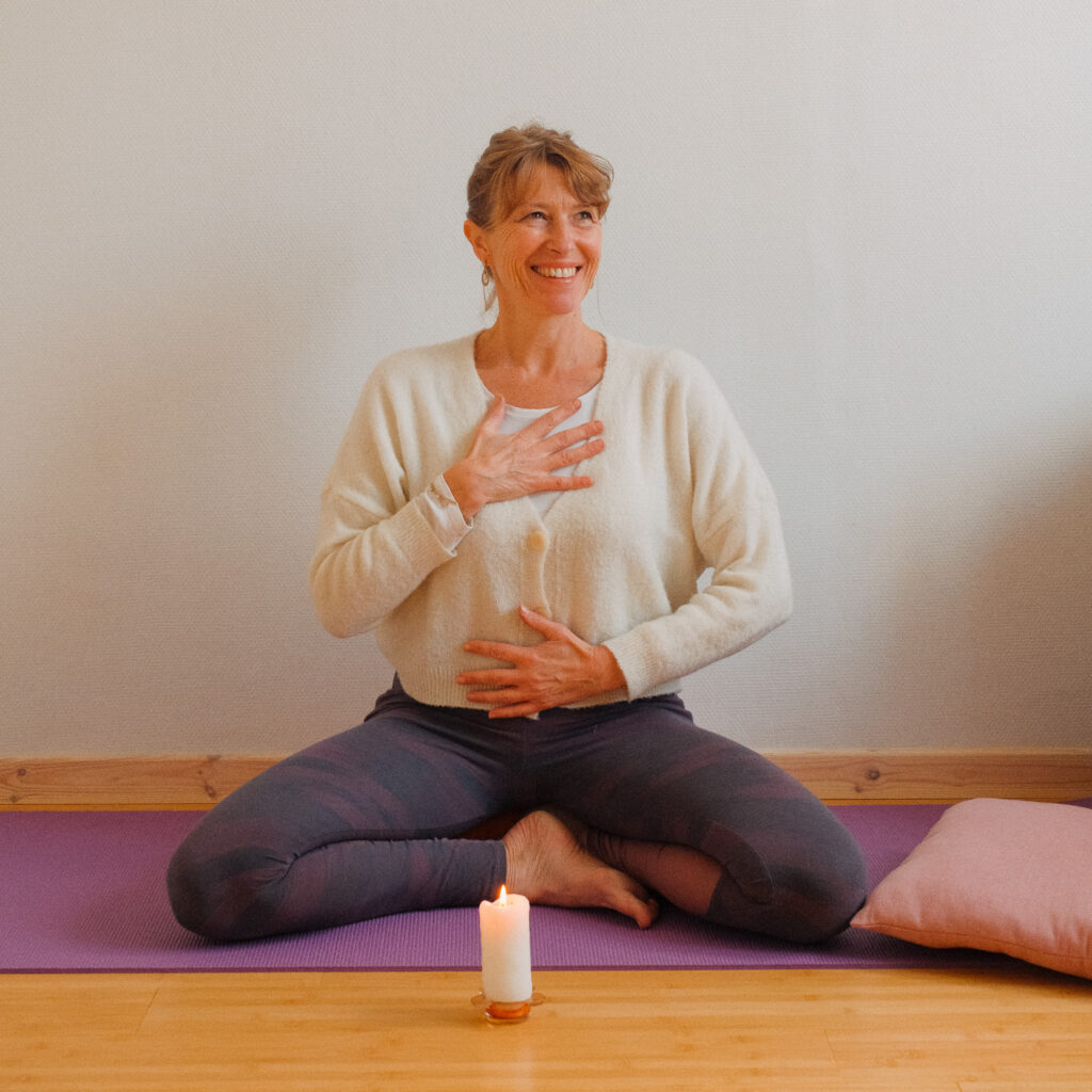 Professeure de yoga et yogathérapeute assise sur un tapis lors d’une séance