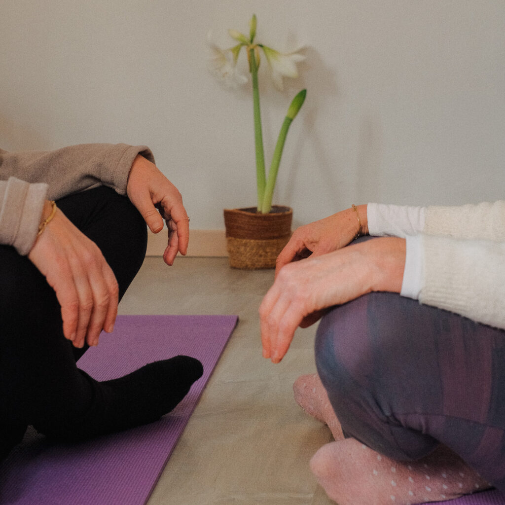 Deux personnes assises face à face sur des tapis de yoga lors d’une séance de yogathérapie individuelle